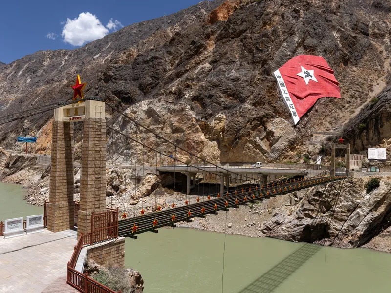 A suspension bridge across a river below steep rock faces