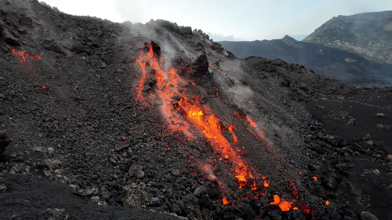 Glowing lava flowing down a dark volcanic slope