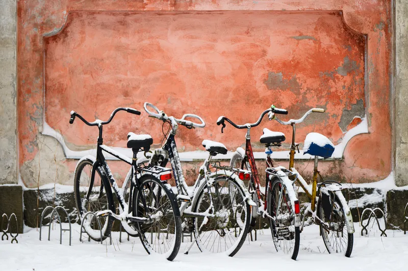 Bicycles covered in snow against an orange wall in Helsinki