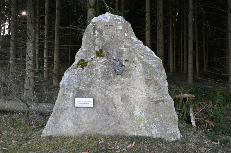 A granite stone with a small plaque in a spruce forest near Arbesbach