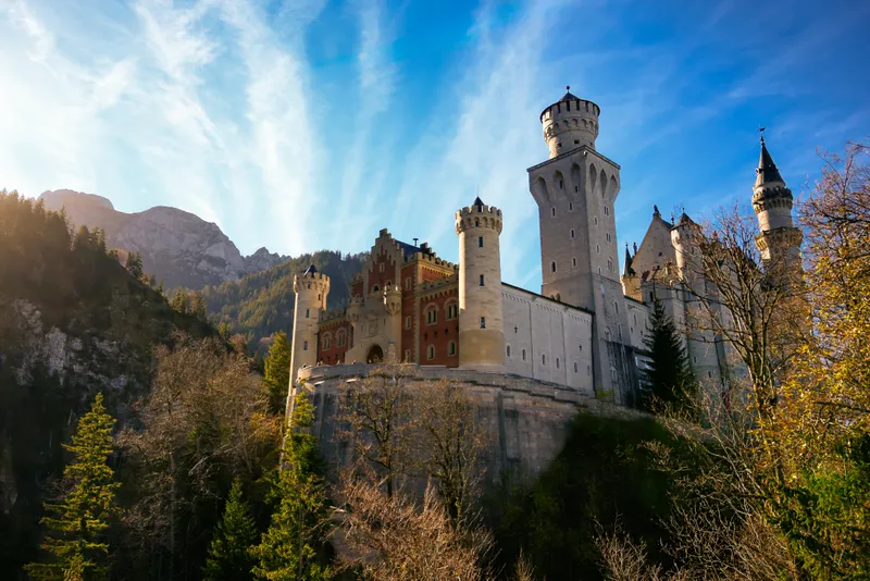 Neuschwanstein Castle above autumn trees under a blue sky
