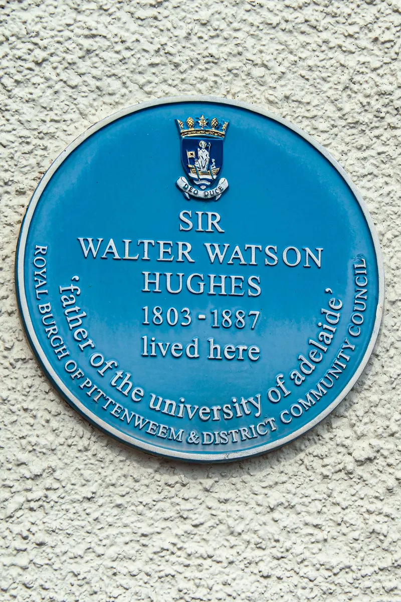 A blue commemorative plaque on a white wall