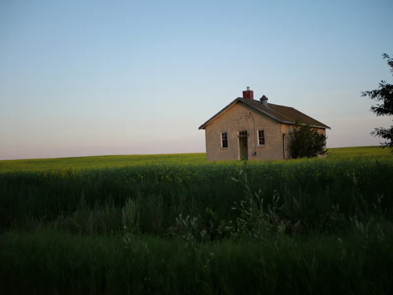 A lone brick building in a green field under an evening sky