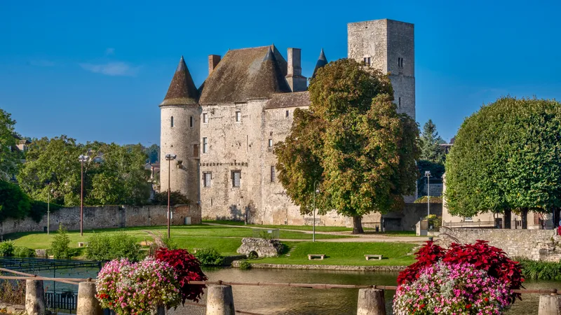 The Château de Nemours behind flower beds and trees on a sunny day