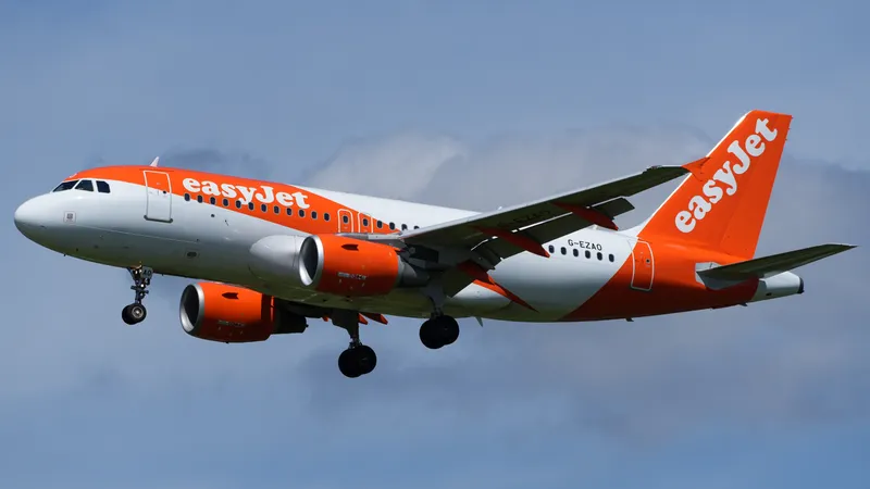 An easyJet Airbus A319 with its landing gear down against a blue sky