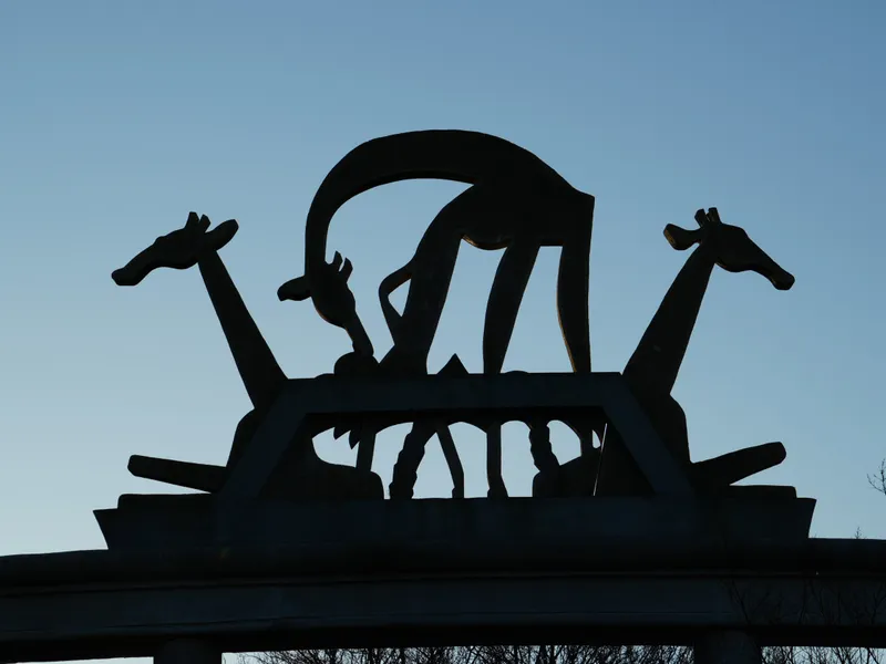 The giraffe sculpture on top of the colonnade at Rotterdam Zoo in silhouette