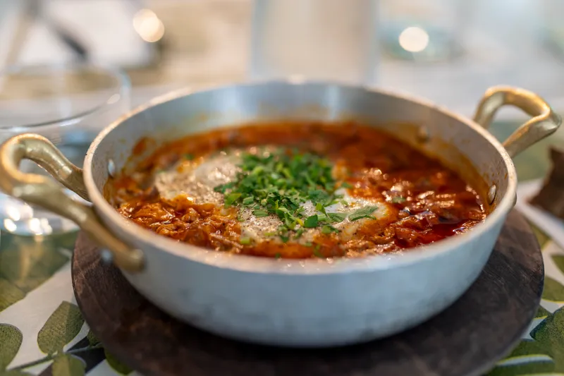 A pan of shakshuka topped with chopped herbs