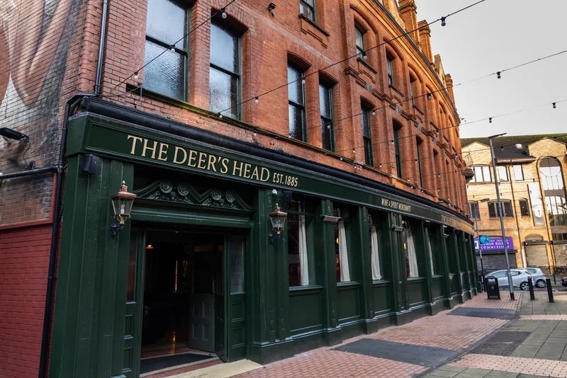 The green front of The Deer's Head pub on a brick street